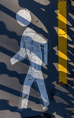 Painted mark of walking person on the pavement with shadows of a fence on top